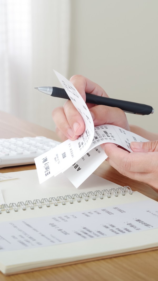 Close-up of someone reviewing receipts and making a list